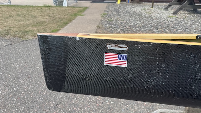 Wenonah J203 Racing Canoe - Graphite Ultra-Light - Wood Inwales w Black Accent, Center Bailer, Integrated Race Seat with Foot Brace - Blem